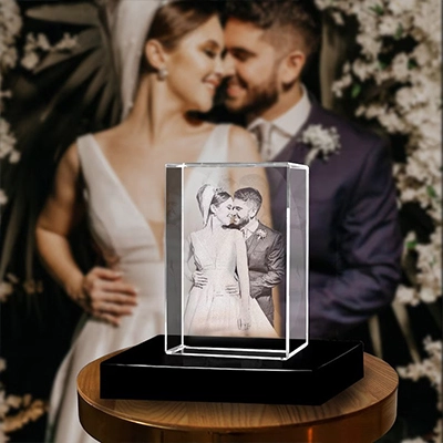 3D crystal photo gift on a black base, featuring an etched wedding couple's portrait with their wedding photo blurred in the background.